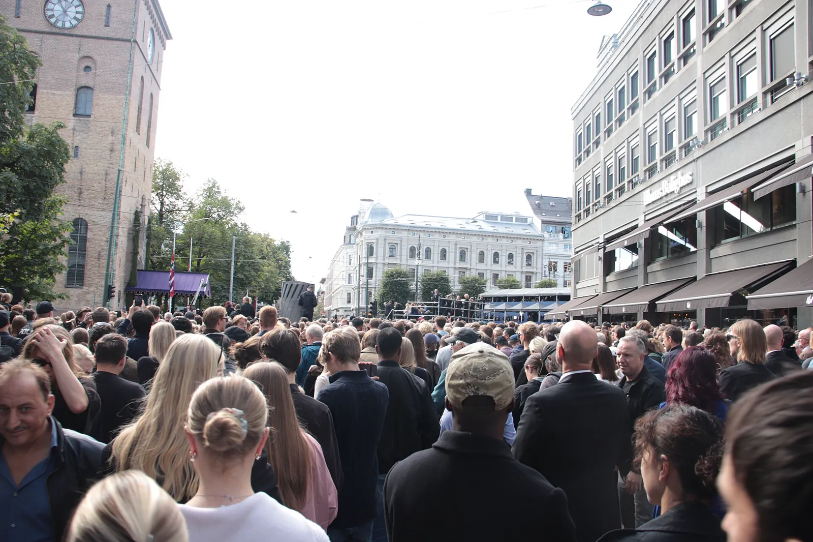 En tett folkemengde i en gate i Oslo på bisettelsesdagen, med Domkirken til venstre i bildet.